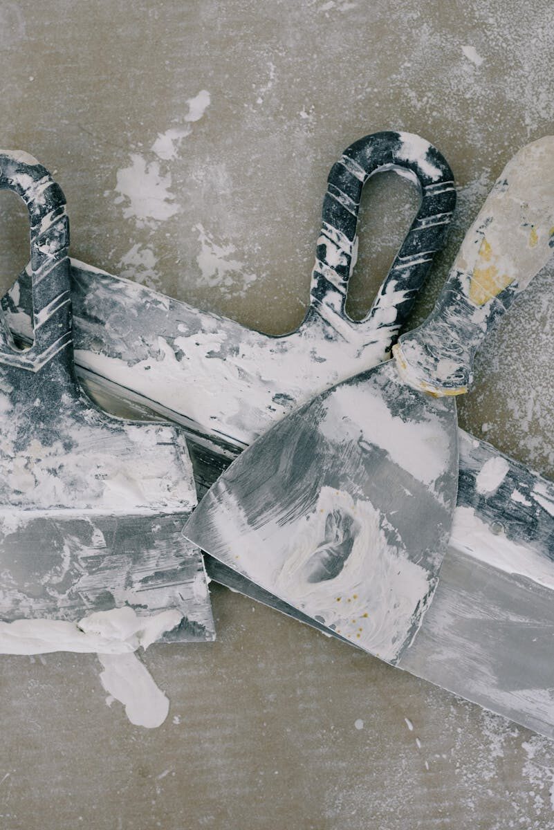 Overhead view of small dirty spatulas covered with white dye on floor with spots in daytime