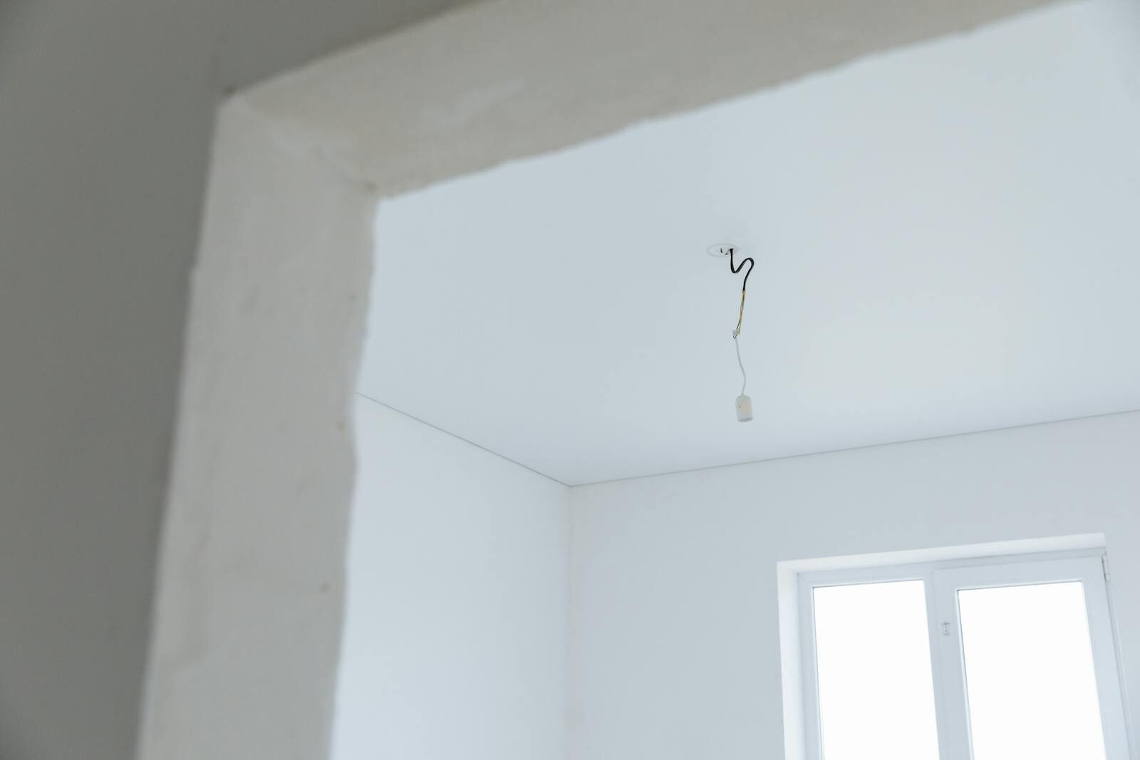 Bright white interior room with exposed electrical wiring and natural light.